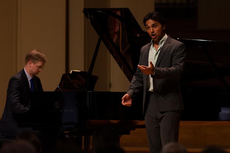 An opera singer performs on stage with a piano accompanist