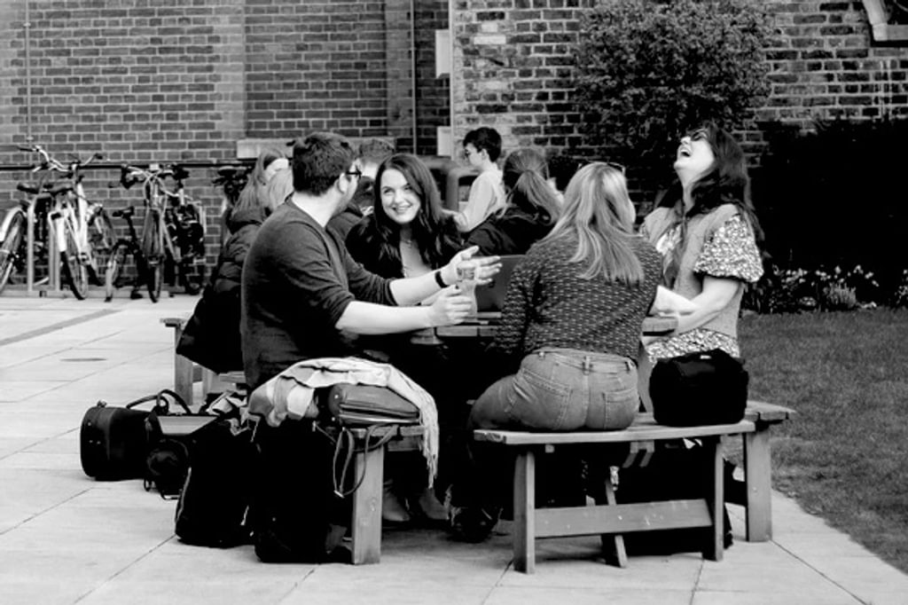 People sit at an outdoor table at the Academy, socialising