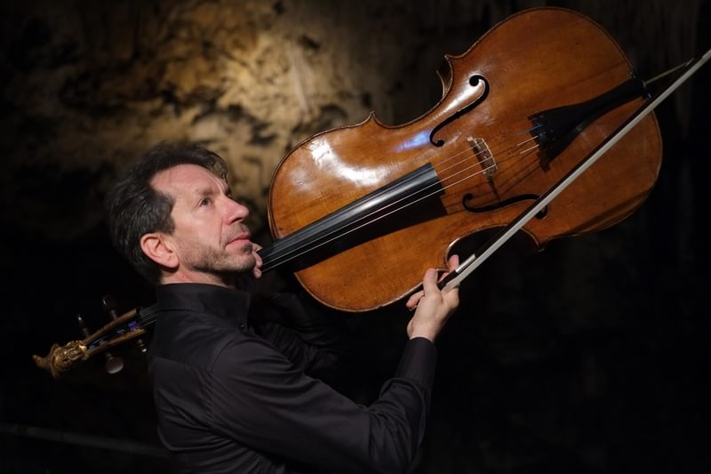Robert Cohen carries a cello on shoulder