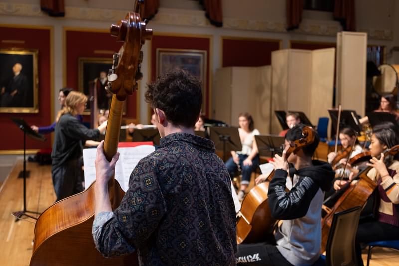 An image of a chamber orchestra in rehearsal, being conducted by Barbara Hannigan
