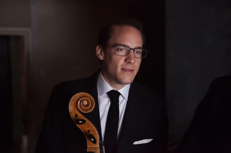 Portrait of a double bass player holding the neck of the instrument, looking off camera