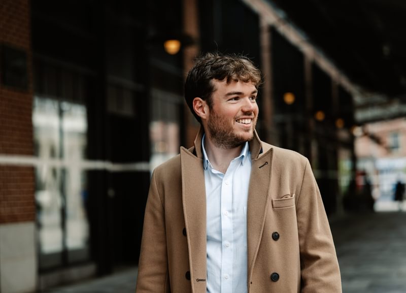 Side portrait of Timothy Ridout outside, smiling to something out of frame
